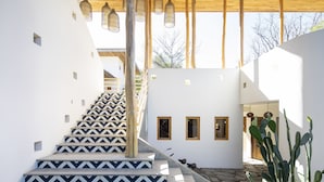 Una escalera con diseños geométricos que lleva a un edificio con techo de madera y luces colgantes.