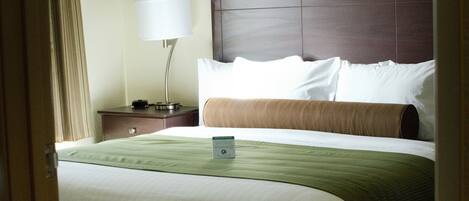 A hotel room with a large bed, a nightstand with a lamp, and a headboard.