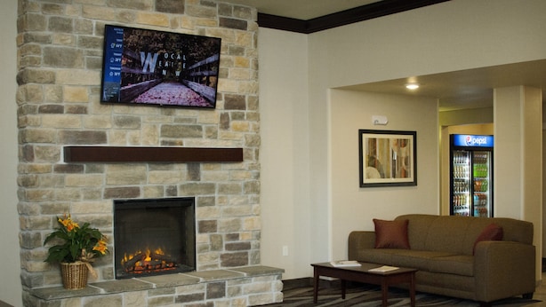 A stone fireplace with a TV mounted above it, a sofa, and a Pepsi refrigerator in the background. - Cobblestone Inn & Suites – Soda Springs (Soda Springs)