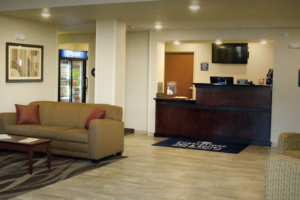 A lobby with a reception desk, a Pepsi refrigerator, a sofa, and a carpet with a logo. - Cobblestone Inn & Suites – Soda Springs (Soda Springs)