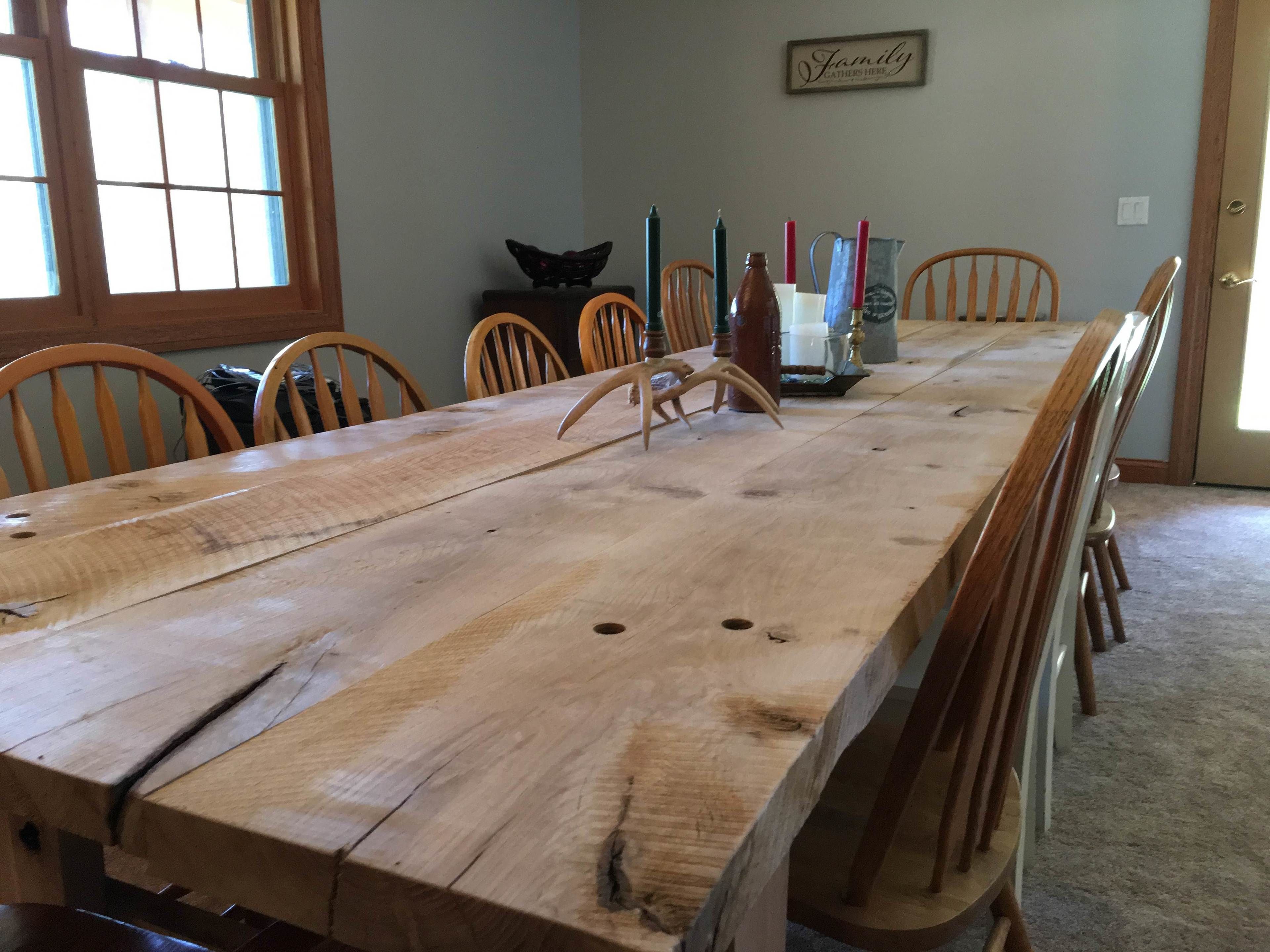 A long wooden dining table with chairs, a decorative butterfly, candles, and a 'Family' sign on the wall.