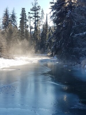 A frozen river with snow-covered trees and a clear sky.