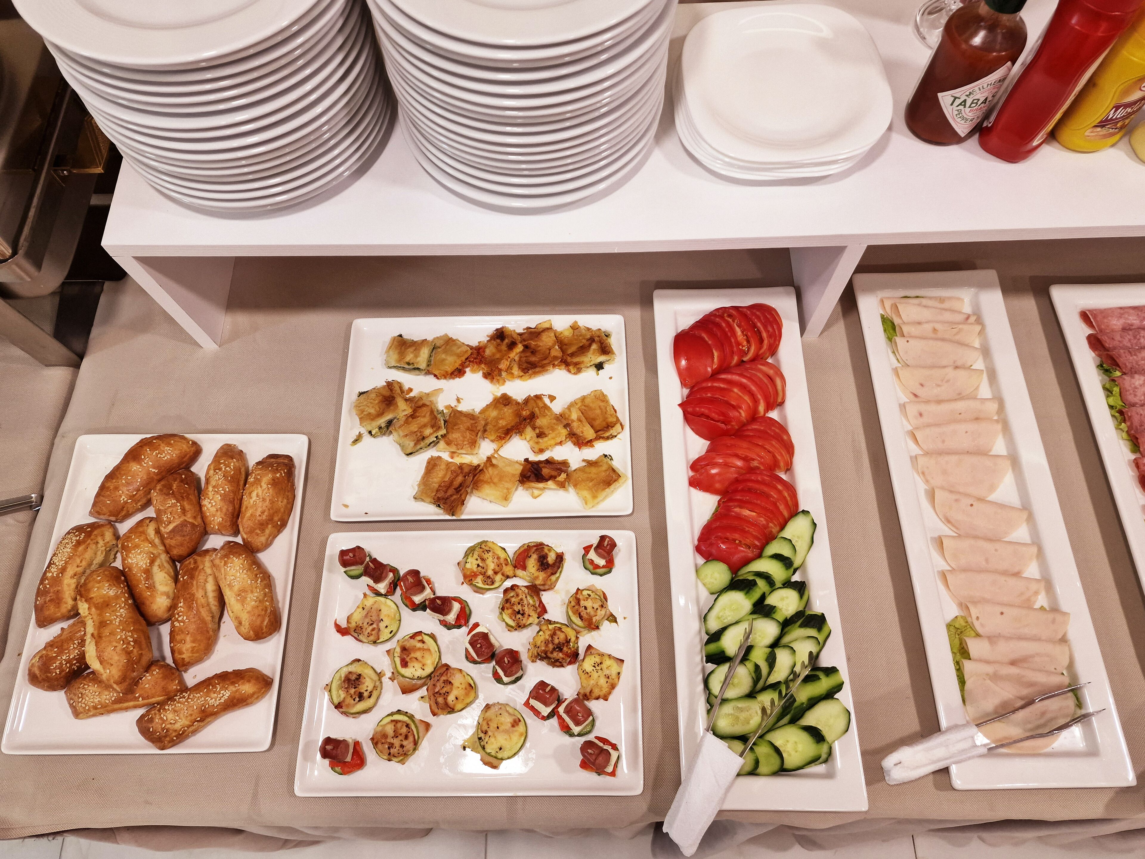 Una mesa de bufé con diversos alimentos, entre ellos pasteles, verduras y carne.
