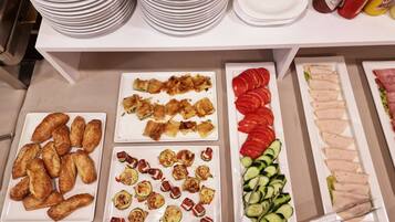 Una mesa de bufé con diversos alimentos, entre ellos pasteles, verduras y carne.