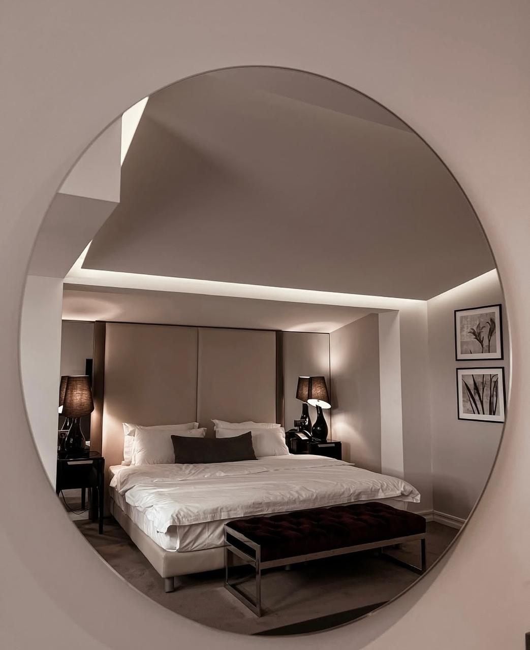 Un dormitorio moderno con una cama grande, mesitas de noche y lámparas de pared.