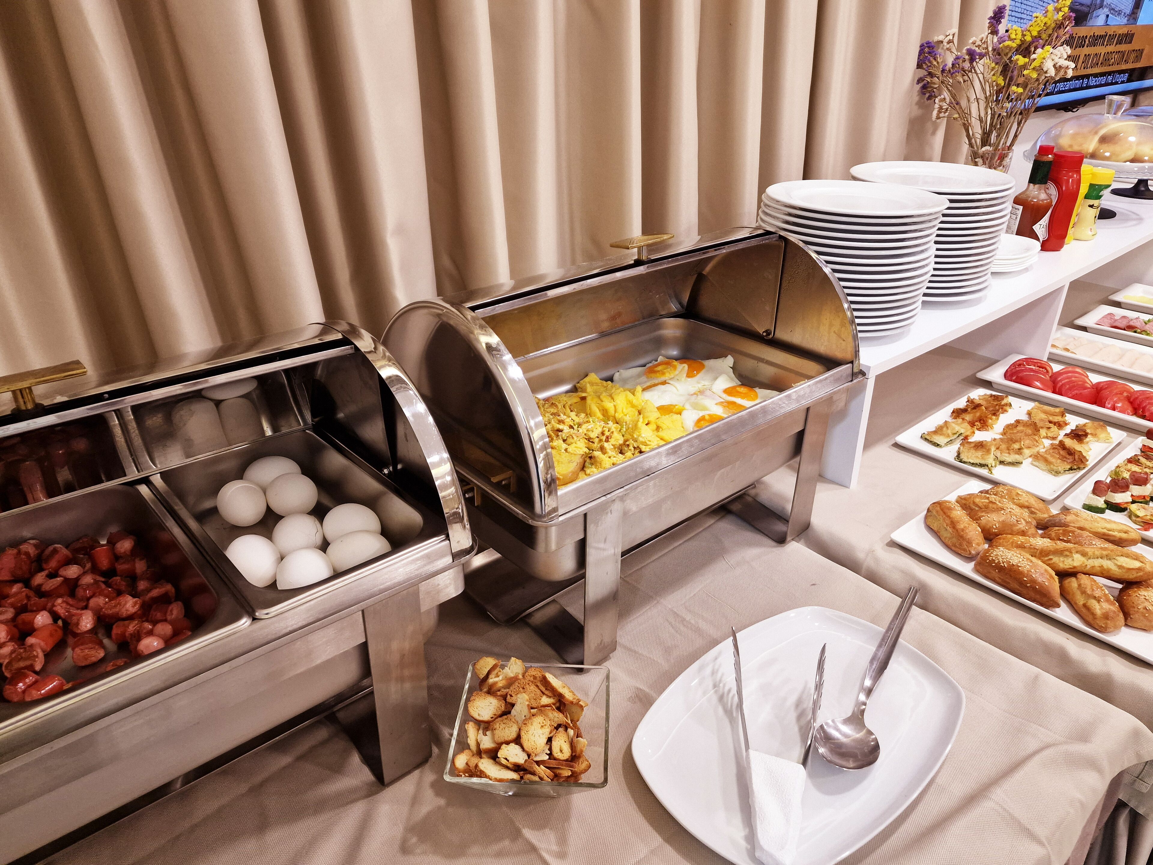 Un bufé con diversas opciones de comida, como huevos, salchichas y pasteles.