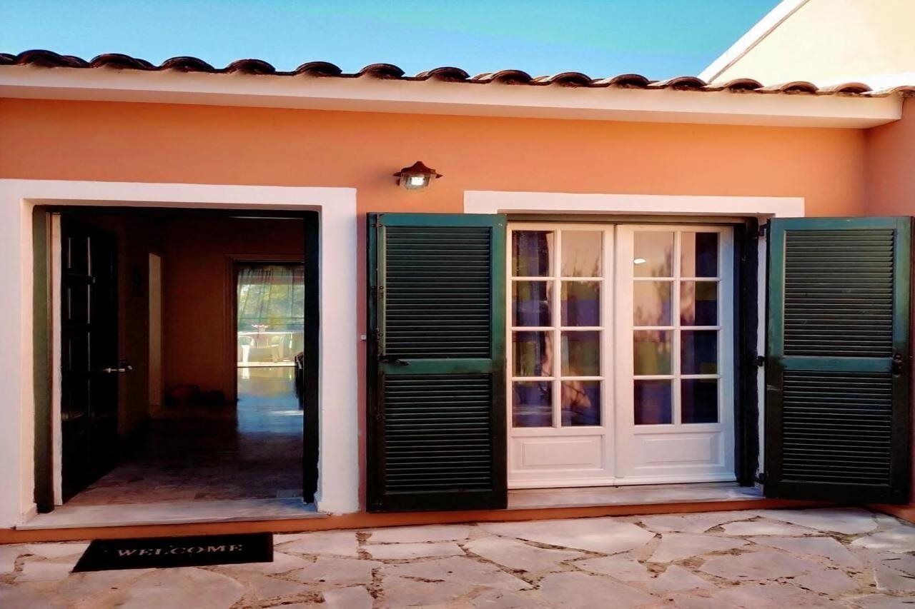 A building entrance with a welcome mat, a door with shutters, and a light fixture above the door.