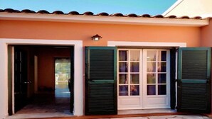 Entrada de un edificio con felpudo, una puerta con contraventanas y un accesorio de iluminación sobre la puerta.
