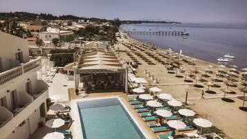 Una piscina al aire libre, sombrillas, sillones reclinables de piscina