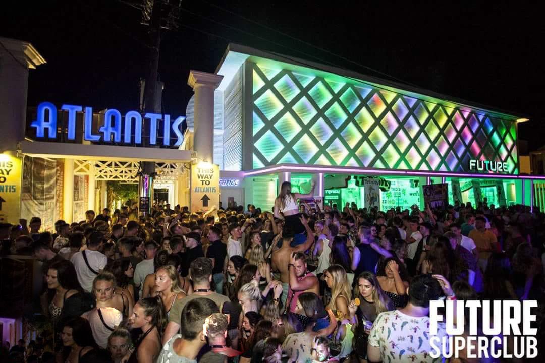 Une discothèque bondée, illuminée par des enseignes au néon indiquant « Atlantis » et « Future Superclub ».