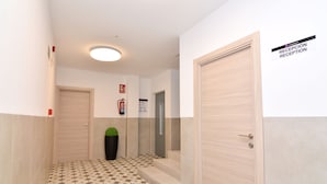 Uma área de recepção com piso de azulejos, balcão de atendimento e placa indicativa da recepção.