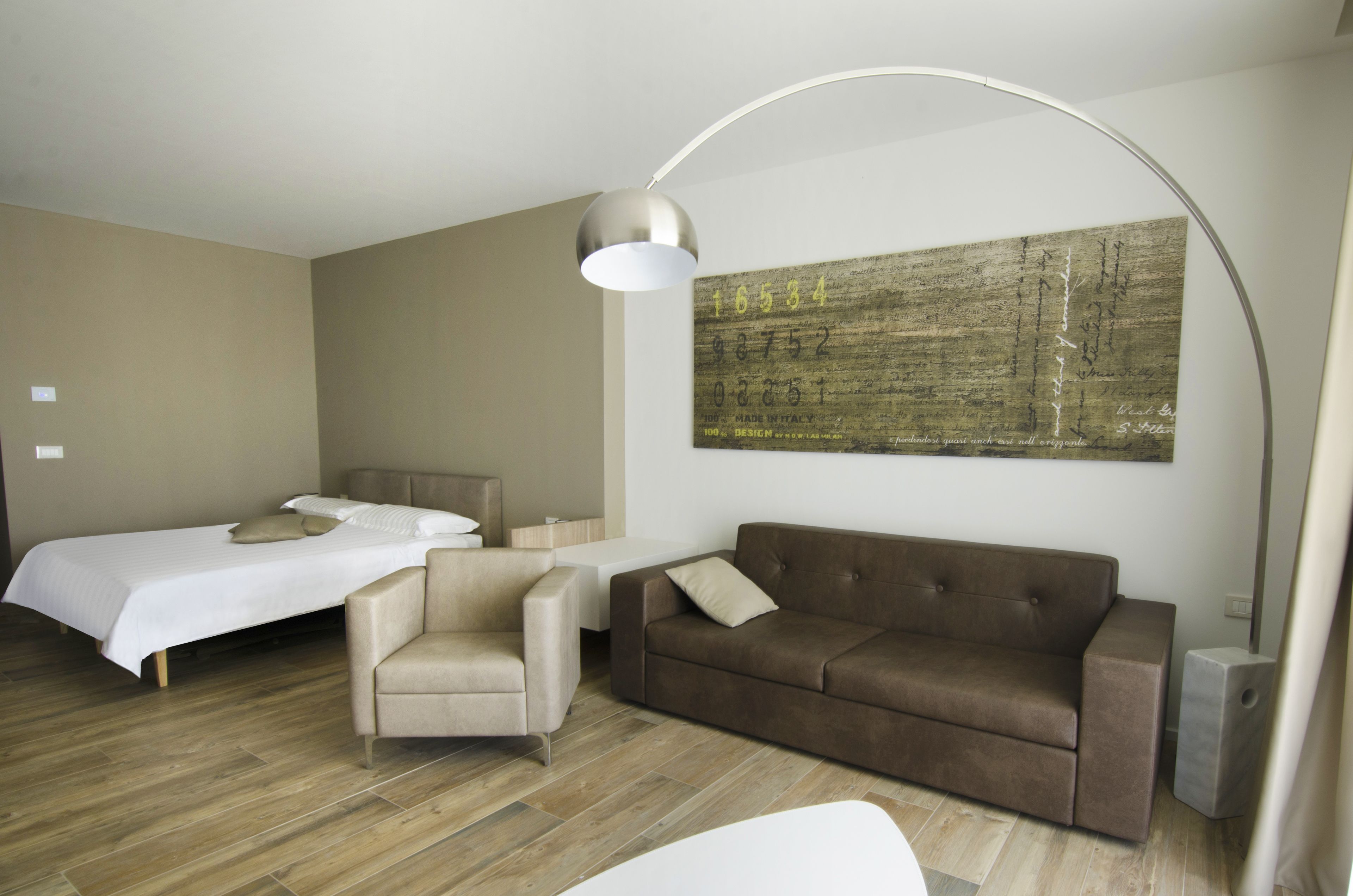 Een moderne hotelkamer met een bed, een slaapbank, een stoel, een bureau en een groot abstract schilderij aan de muur.