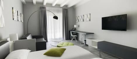 Een moderne hotelkamer met een groot bed, een bureau, een stoel en een aan de muur bevestigde televisie.