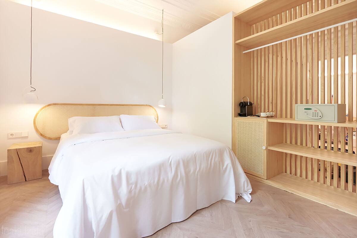 Une chambre à coucher moderne avec une tête de lit en bois, une table de chevet, une bibliothèque intégrée et une lampe de chevet.