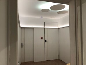 En smal hall med ett tak som har infälld belysning och ett tydligt synligt nummer, ’01’, på väggen.