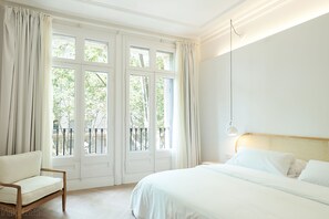 A bedroom with a large bed, a chair, and a window with curtains. - The Mohouse Boutique Room (Barcelona)