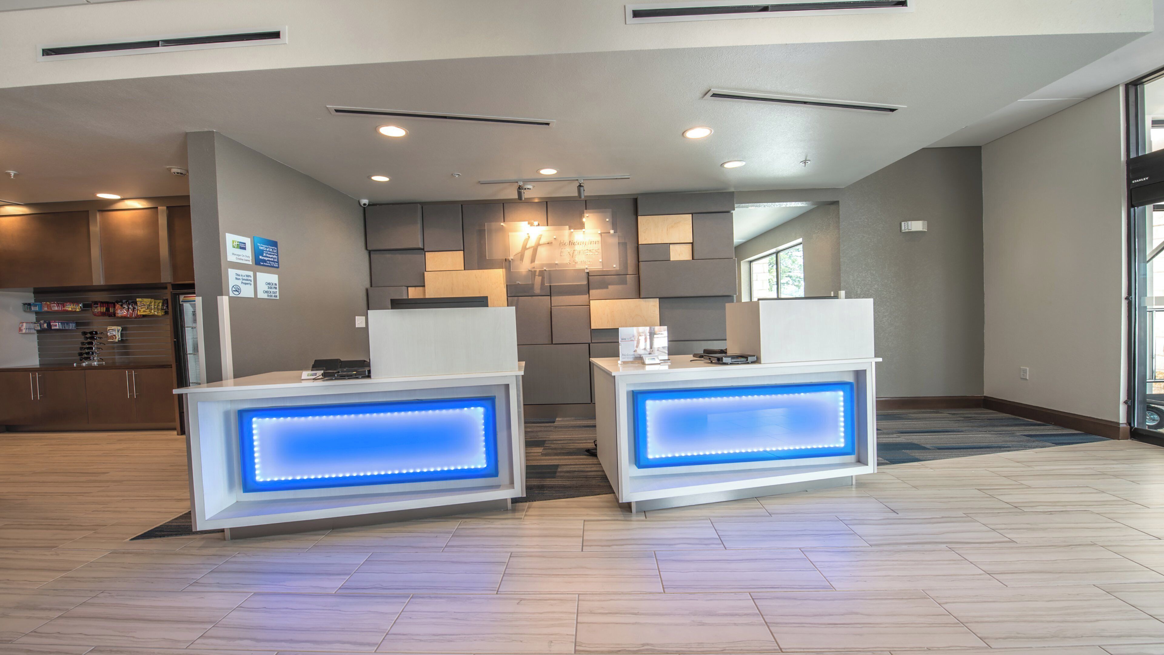 A reception area with two illuminated counters, a modern kitchen in the background, and a large window providing natural light.