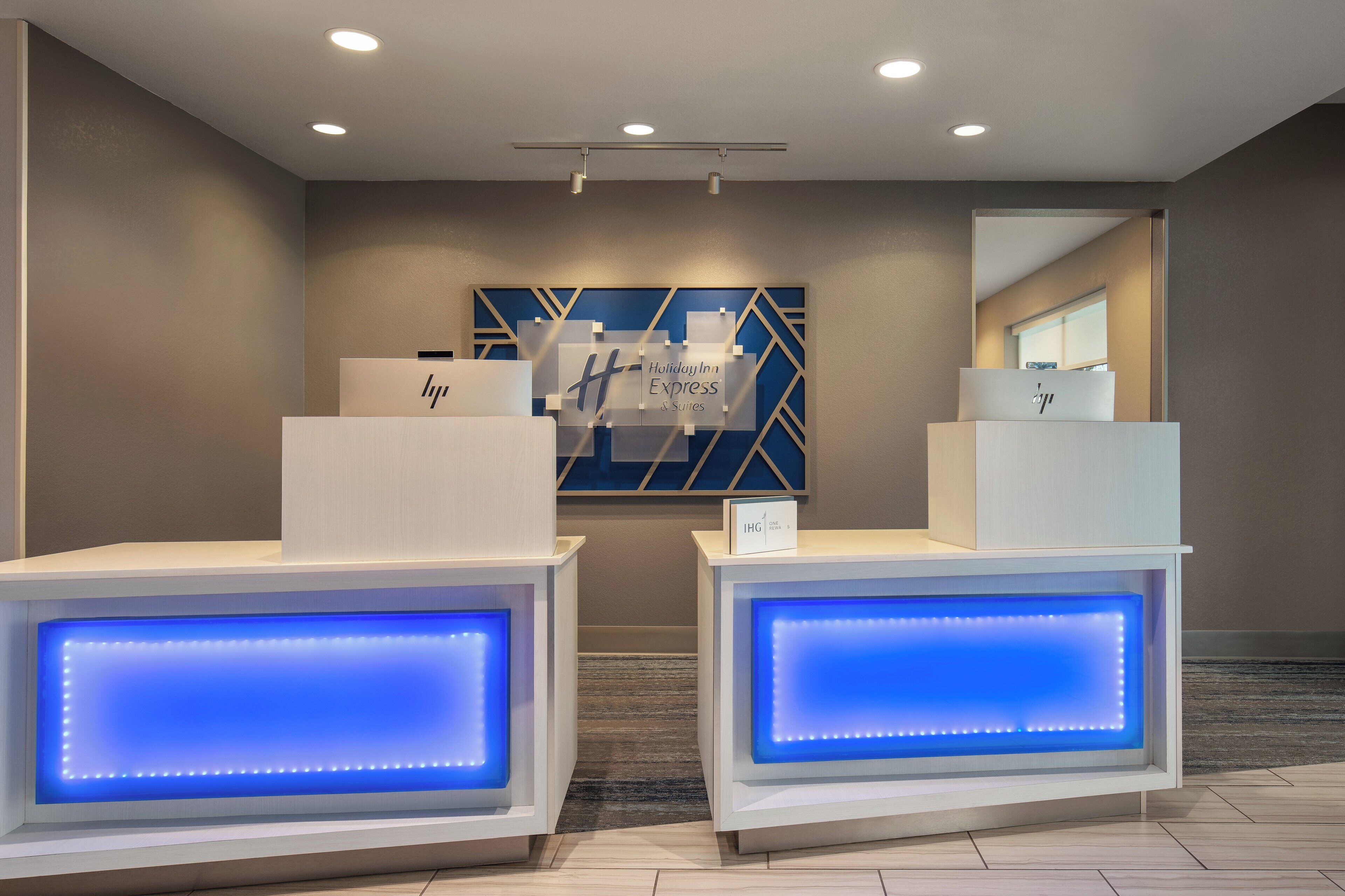 A reception area with two illuminated reception desks, a wall-mounted sign, and a geometric wall design.