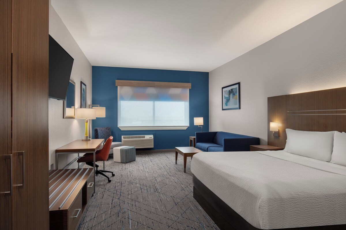 A hotel room with a bed, desk, chair, and a sofa.