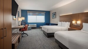 A hotel room with two beds, a desk, a chair, a window with blinds, and a wall-mounted TV.