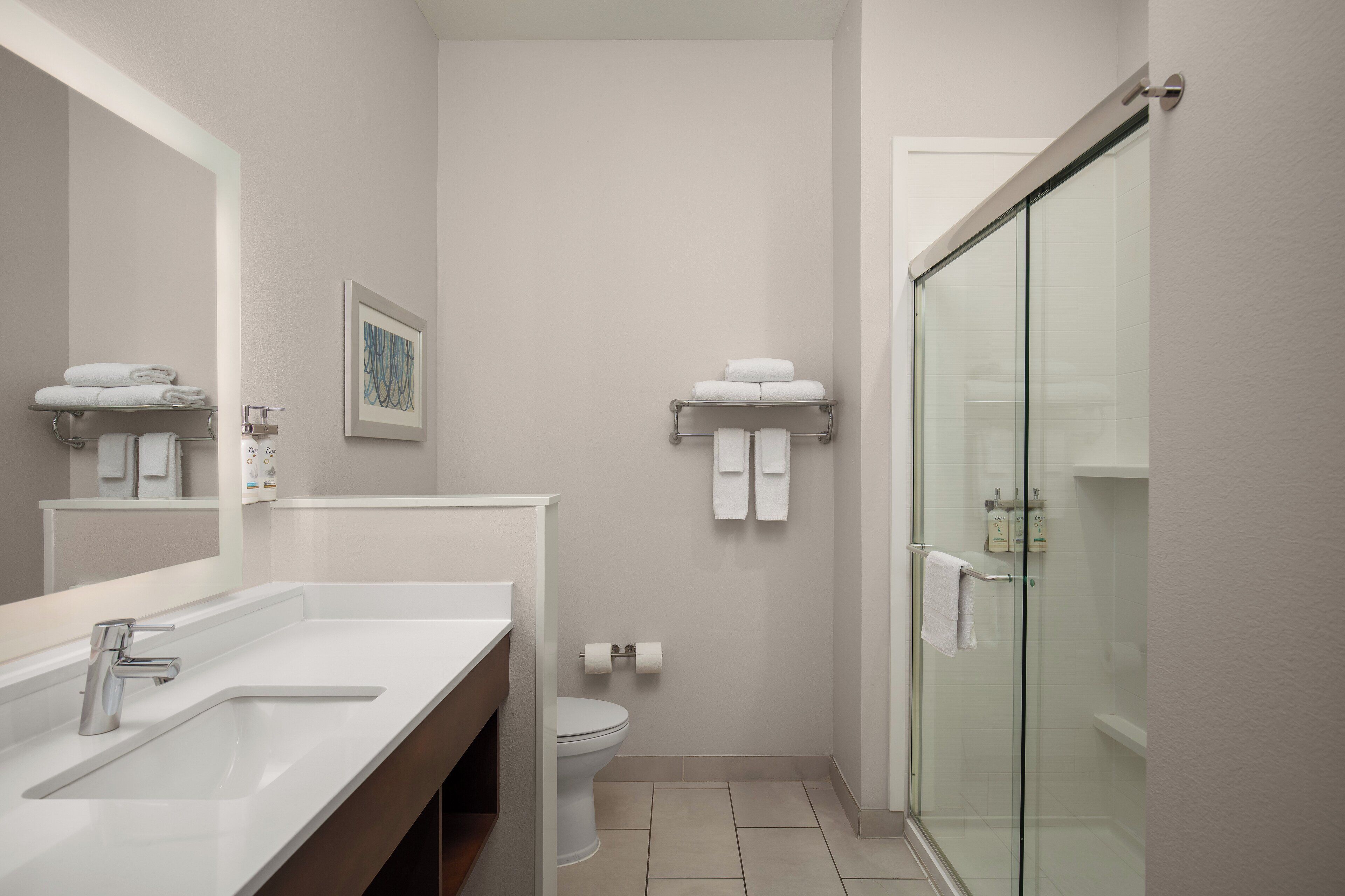 Un baño moderno con cabina de ducha de vidrio, un lavabo blanco y un inodoro.