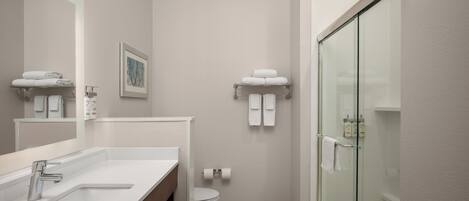 Un baño moderno con cabina de ducha de vidrio, un lavabo blanco y un inodoro.