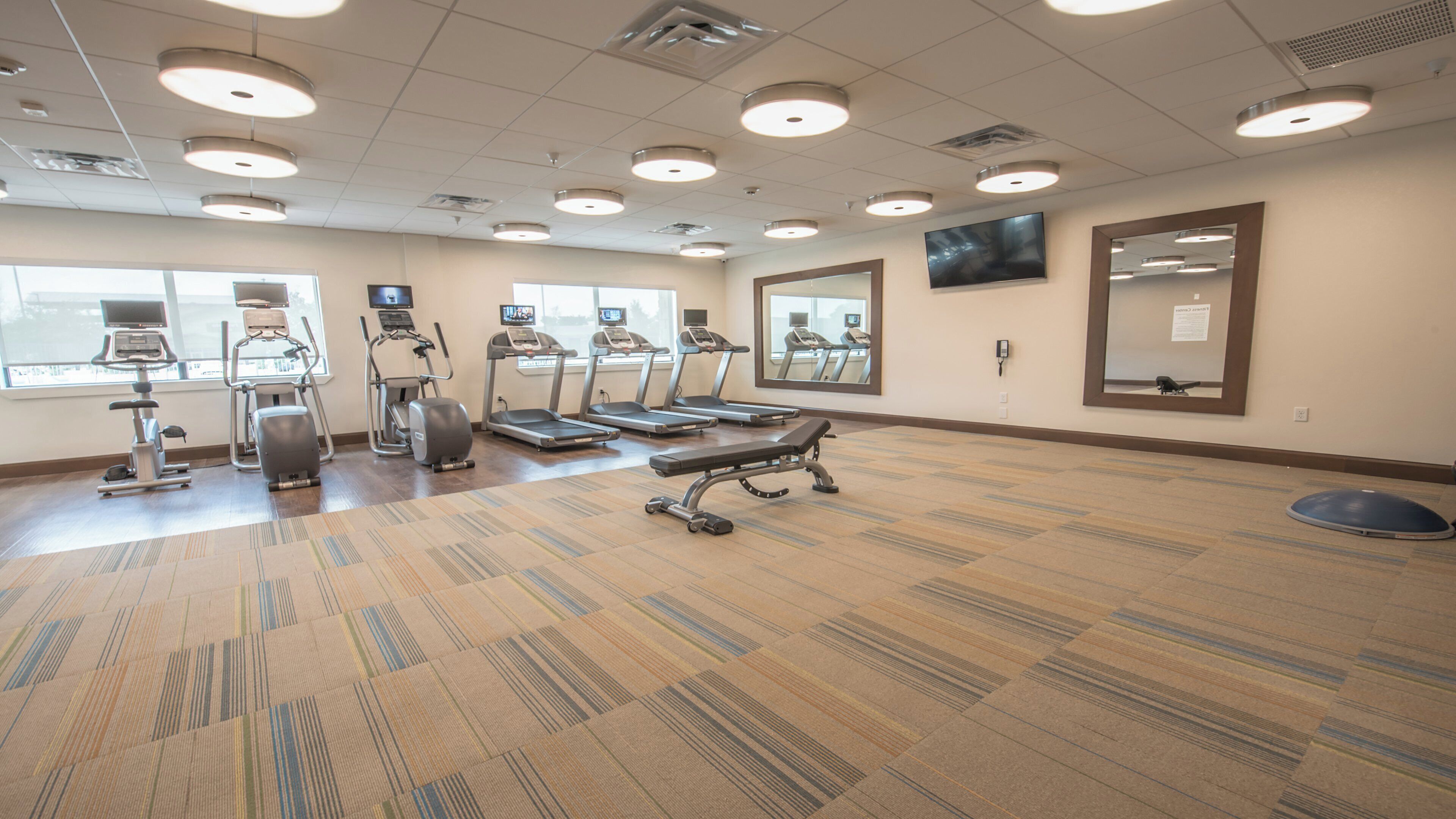 Un centre de remise en forme équipé de tapis de course, de vélos elliptiques et d’un vélo d’appartement.