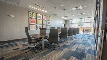 A conference room with a long table, six chairs, and framed artwork on the wall.
