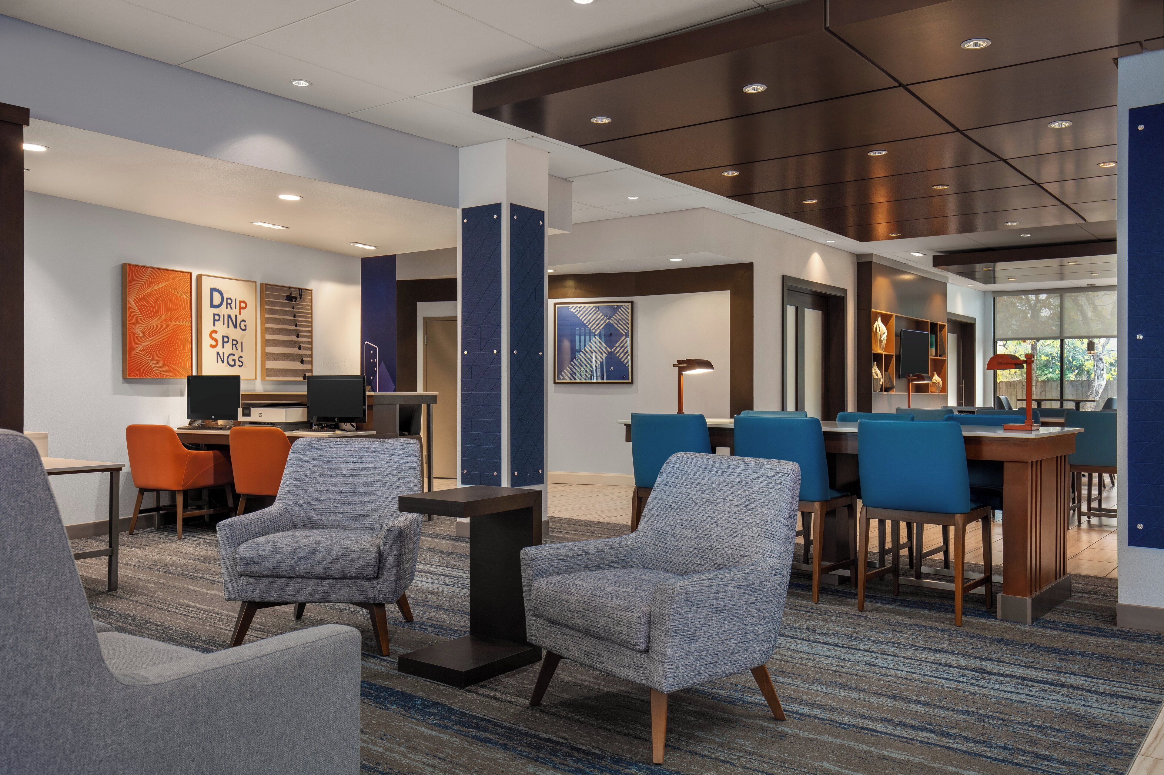 A hotel lobby with seating areas, a reception desk, and artwork on the walls.
