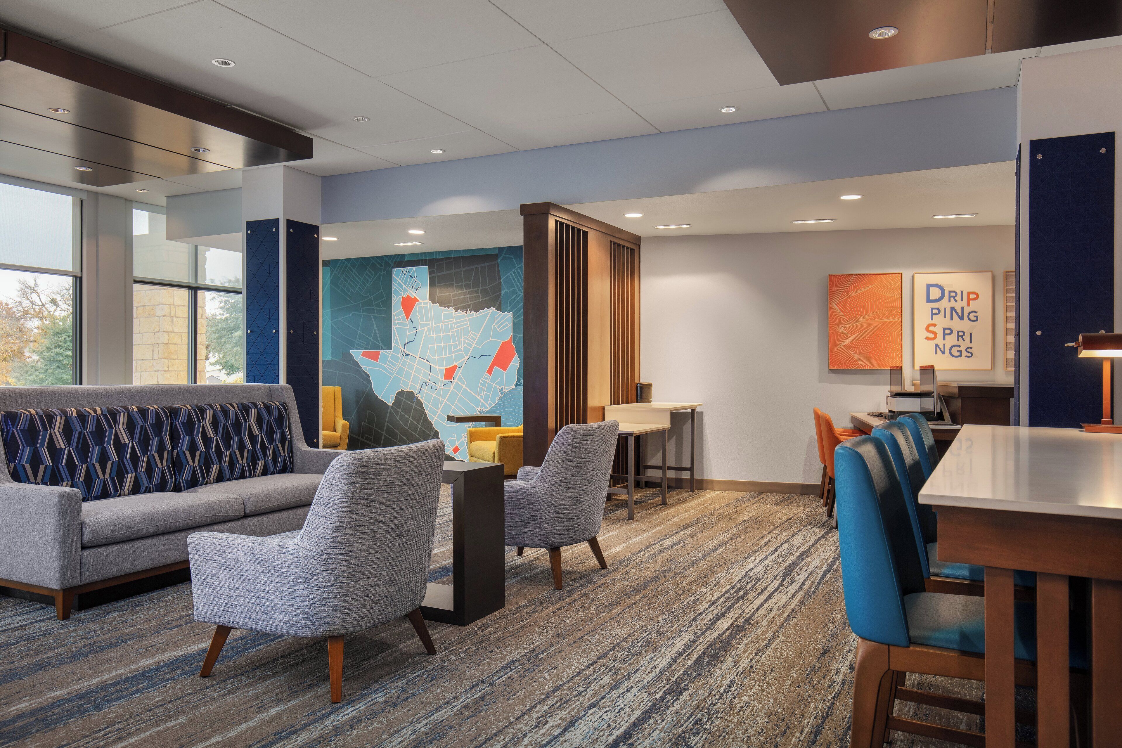 A modern hotel lobby with a sofa, chairs, a dining table, and a large map mural.