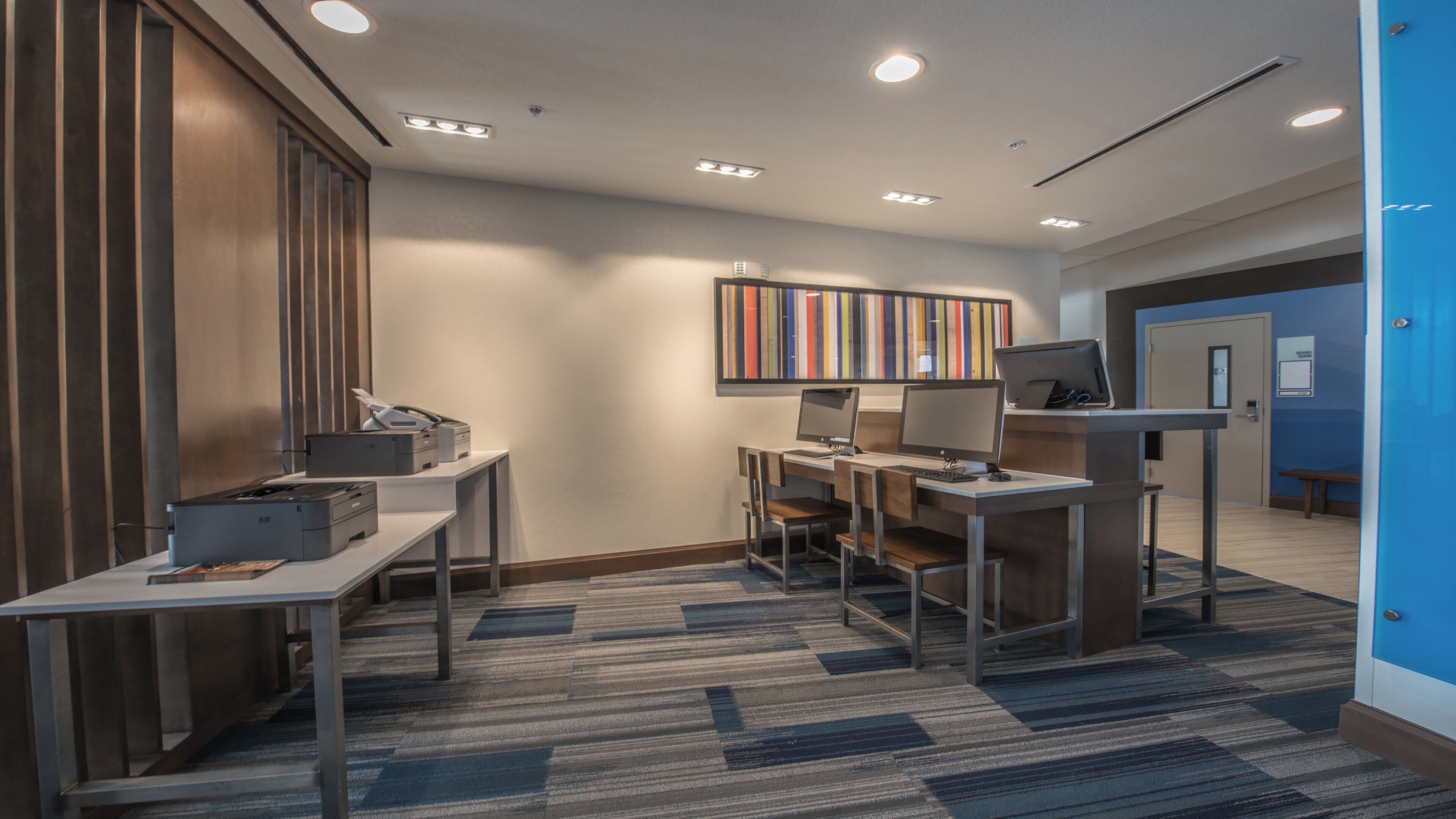 A modern office space with desks, computers, and printers.