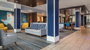 A modern lobby with seating areas, a map mural, and a bar/lounge area.