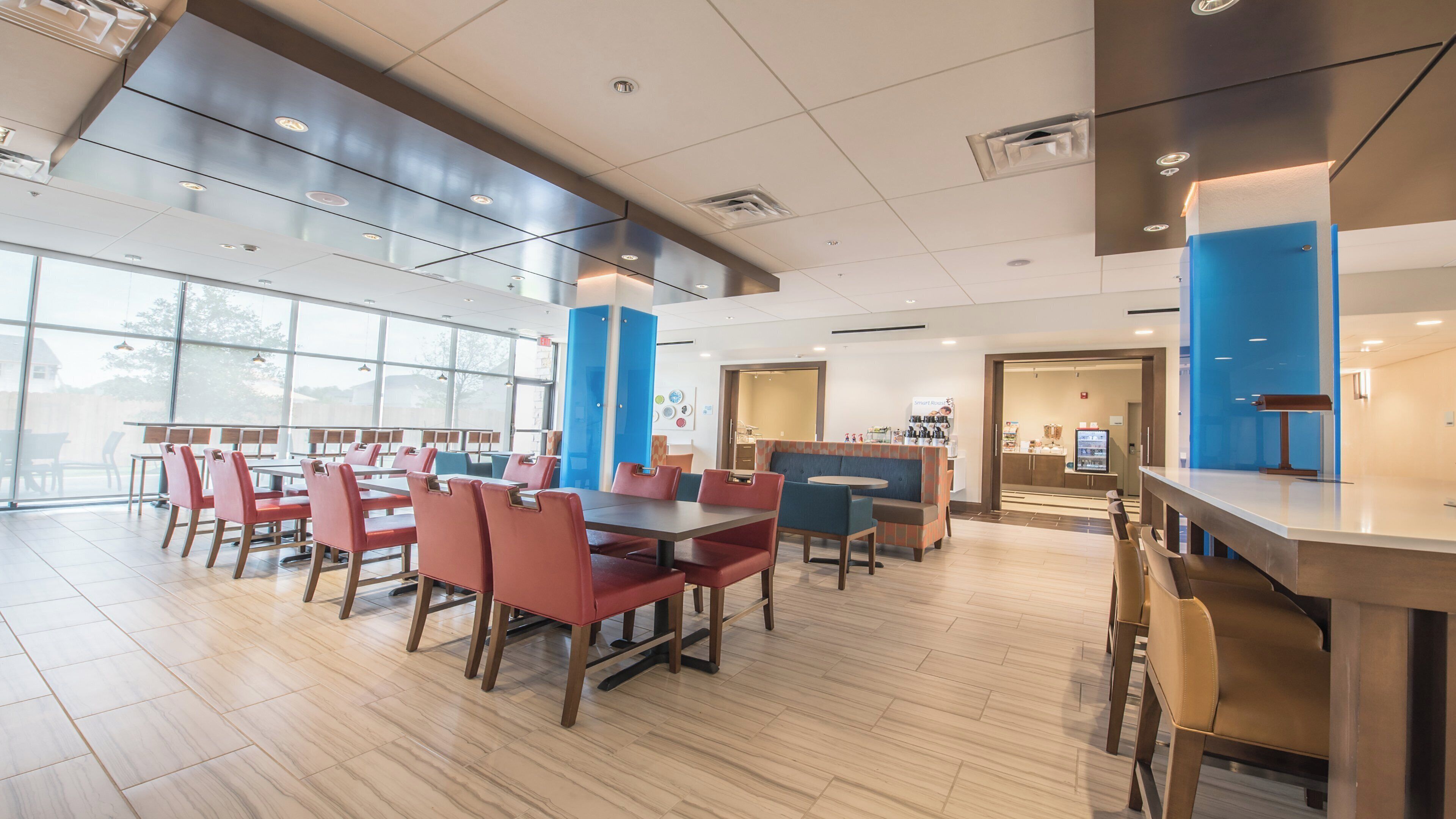 Un comedor interior amplio con techos altos, ventanas grandes y diversas opciones de asientos, incluyendo mesas y cabinas.