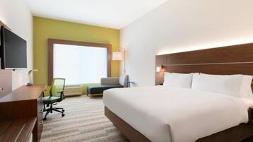 A hotel room with a large bed, a desk, a chair, a television, and a window with a view.