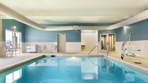 Une piscine à l’eau d’un bleu limpide, un vestiaire et un espace d’accueil avec des chaises et un bureau.