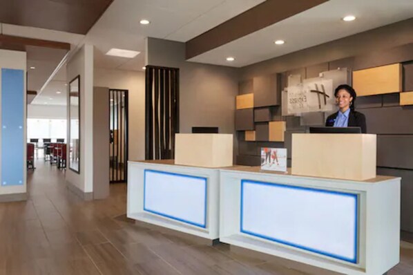 A reception area with a modern design, featuring a reception desk, a large clock, and a framed artwork on the wall. - Holiday Inn Express and Suites-Cincinnati NE - Red Bank Road by IHG (Cincinnati)
