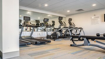 A fitness center with treadmills, elliptical machines, and a weight bench.