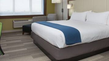 A hotel room with a bed, a desk, a chair, a TV, and a window.