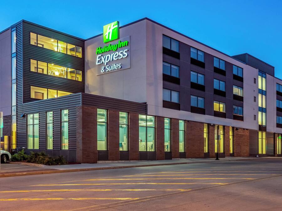 Un hotel Holiday Inn Express & Suites dall'architettura moderna, con un cartello ben visibile, ampie finestre e un parcheggio.
