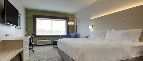 A hotel room with a bed, desk, chair, and a television mounted on the wall.