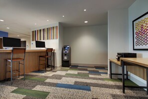 A modern office space with a reception desk, two computer monitors, a cash machine, and a patterned carpet. - Holiday Inn Express and Suites-Elizabethtown North by IHG (Elizabethtown)