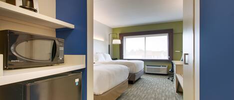 A hotel room with a microwave, refrigerator, two beds, a window, and a desk.