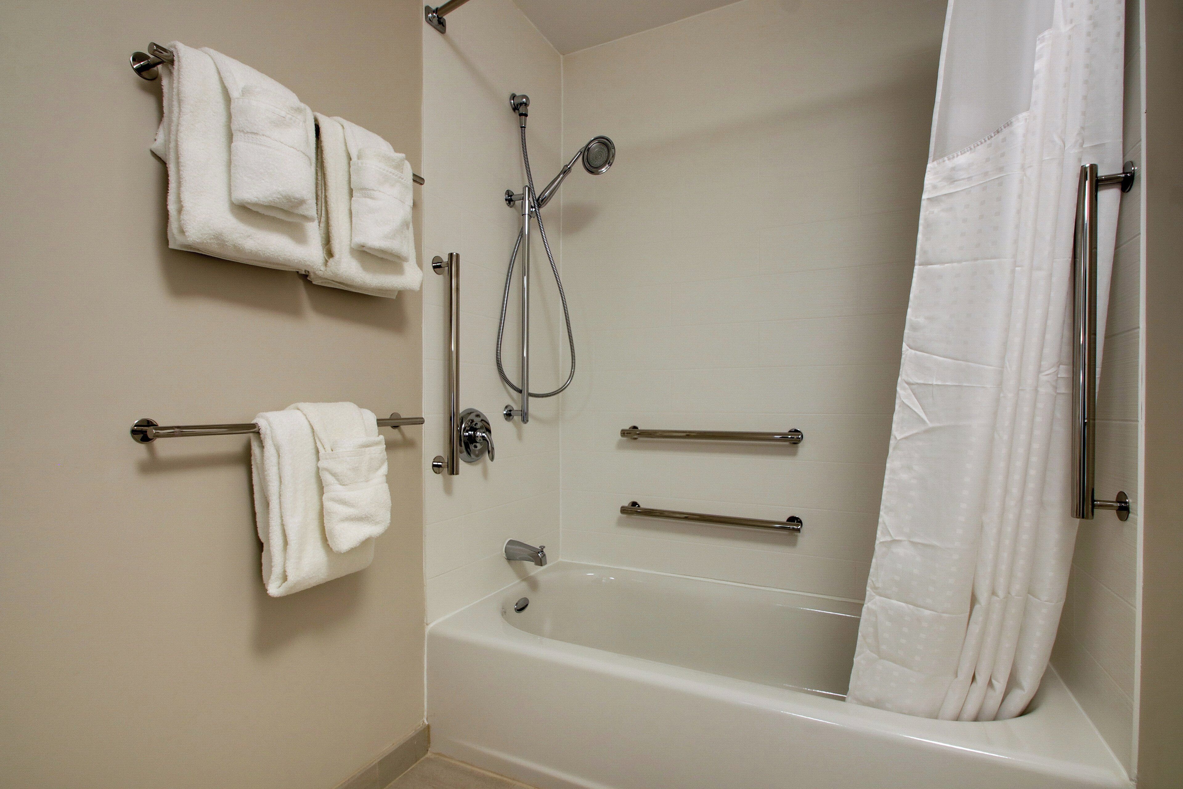 A bathroom with a bathtub, a shower, and two towel racks with towels.