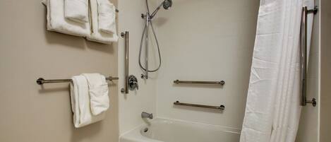 A bathroom with a bathtub, a shower, and two towel racks with towels.