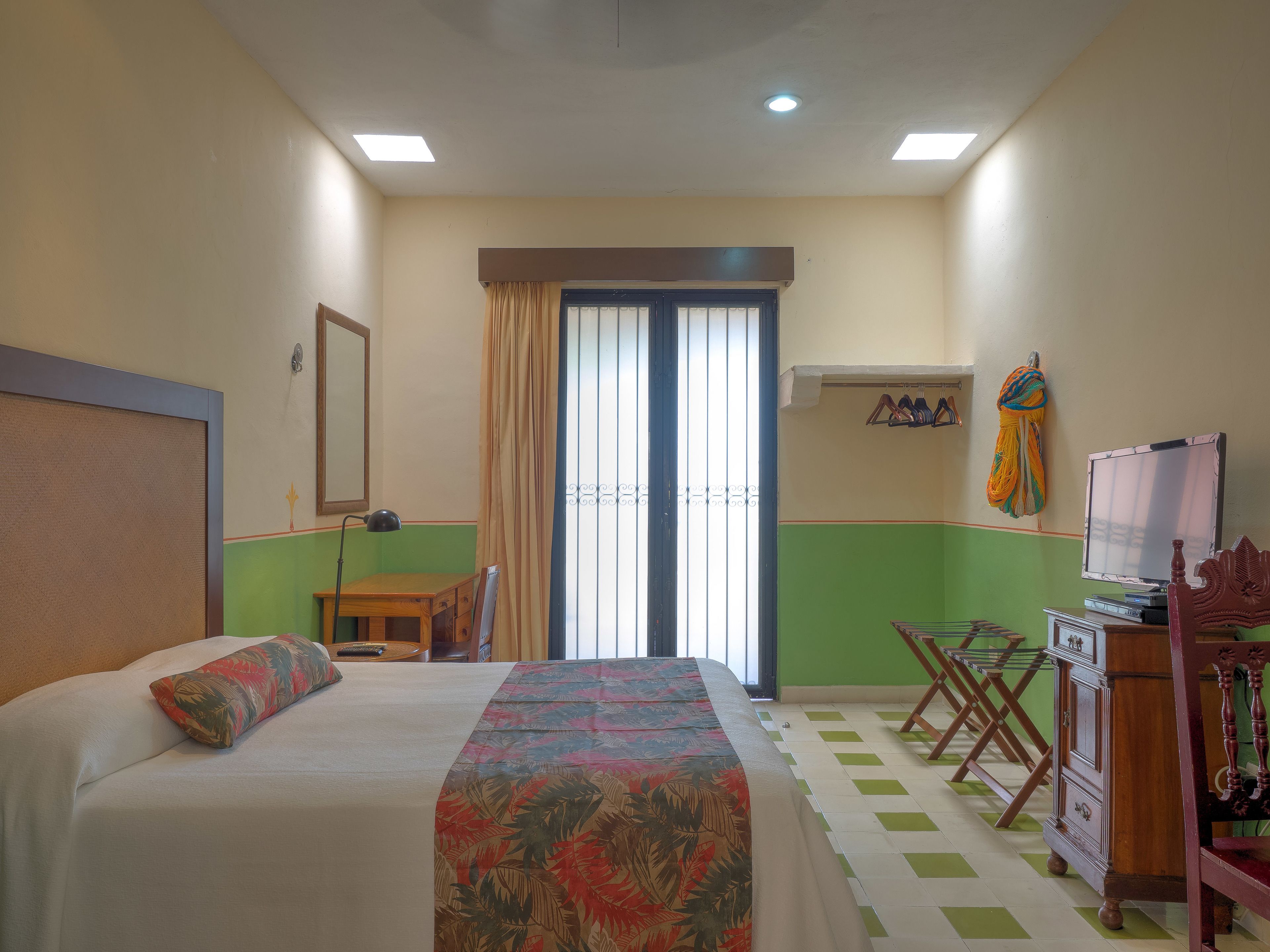 Una habitación de hotel con una cama, un escritorio, una silla, un televisor y un armario.