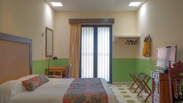 Una habitación de hotel con una cama, un escritorio, una silla, un televisor y un armario.