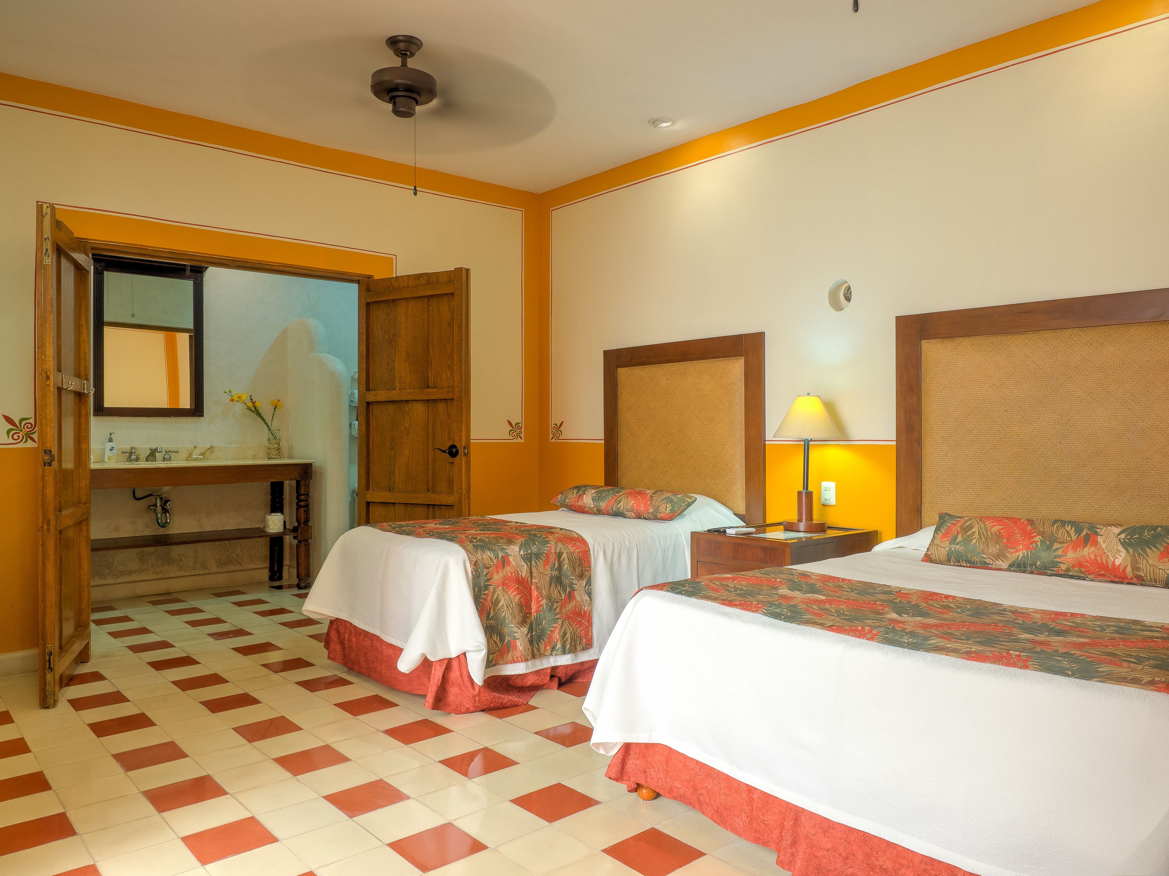 Habitación de hotel con dos camas, un armario de madera, un baño con espejo y una recepción.