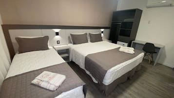 Habitación de hotel con dos camas, un escritorio y un armario.