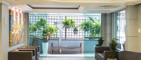 A modern lobby with a bench, sofas, and potted plants.