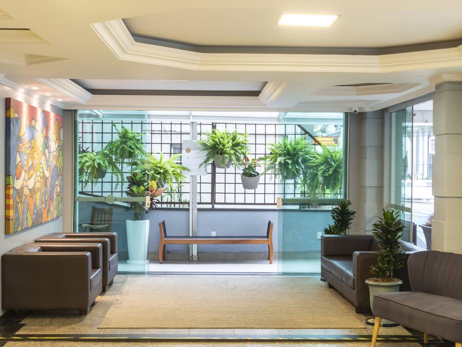 A modern lobby with a bench, sofas, and potted plants.